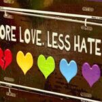 There is a saying at the top: “More Love. Less Hate.” Underneath are five different colored hearts. The first heart is broken.